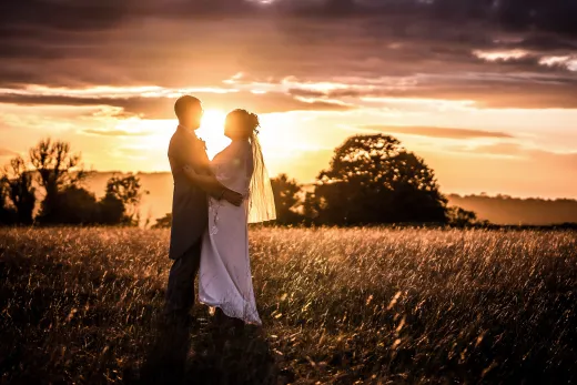 Best wedding photographer capturing a couple in a field at sunset.