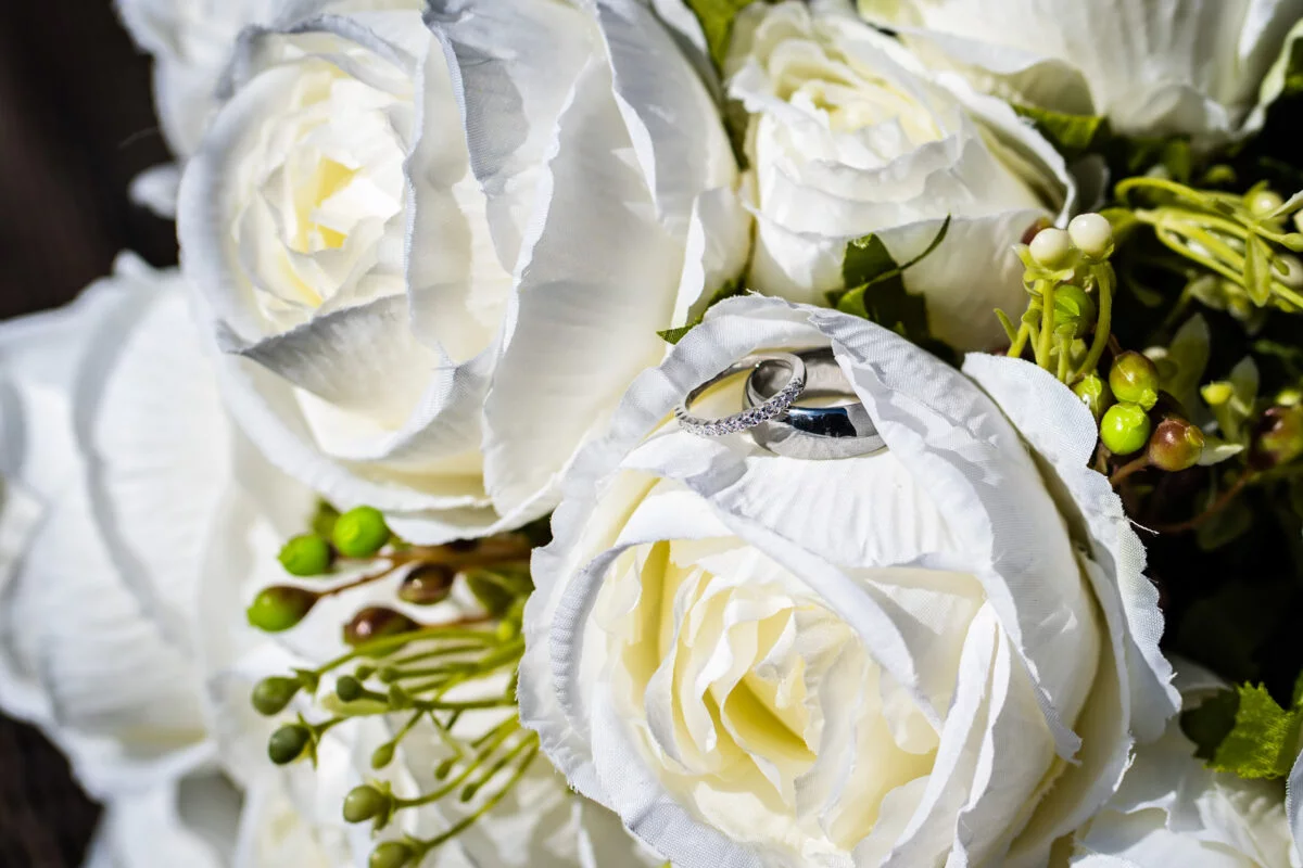A bouquet of white roses with a wedding ring.