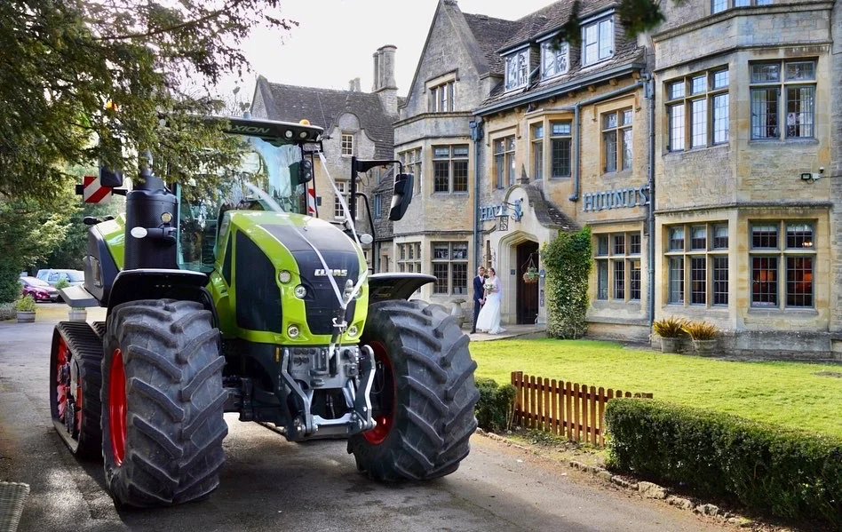 A tractor driving down the road in front of a large house.