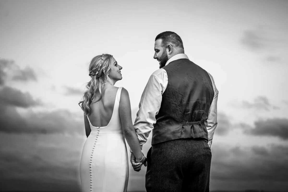 A bride and groom holding hands on the beach.