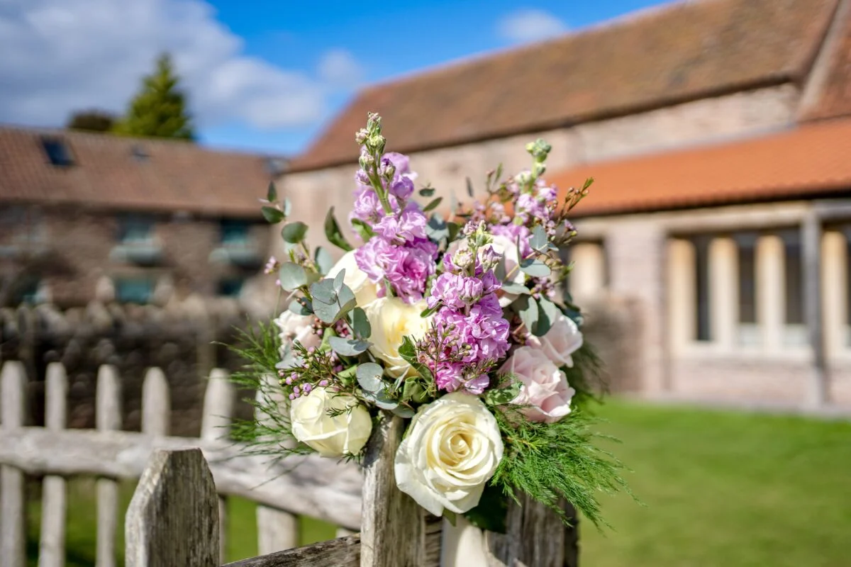A wedding bouquet on a wooden fence in front of a church.