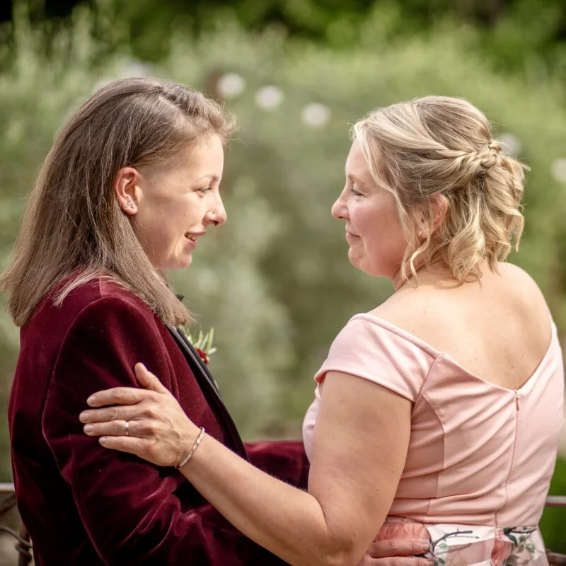 Two women hugging each other in a garden.