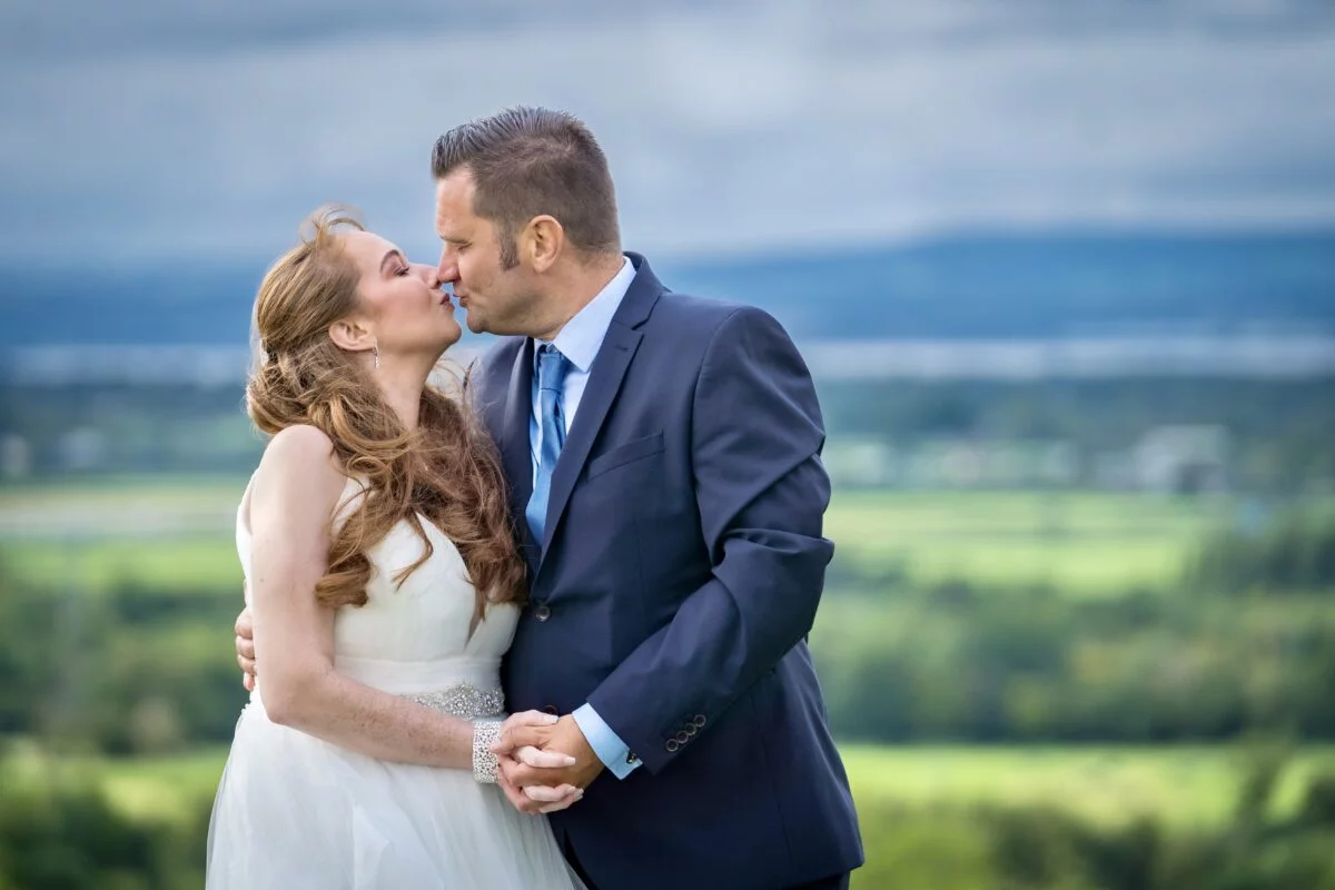 A bride and groom kissing in front of a field.