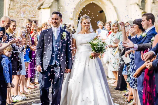 The best wedding photographer in Bristol captures a bride and groom walking down the aisle with confetti.