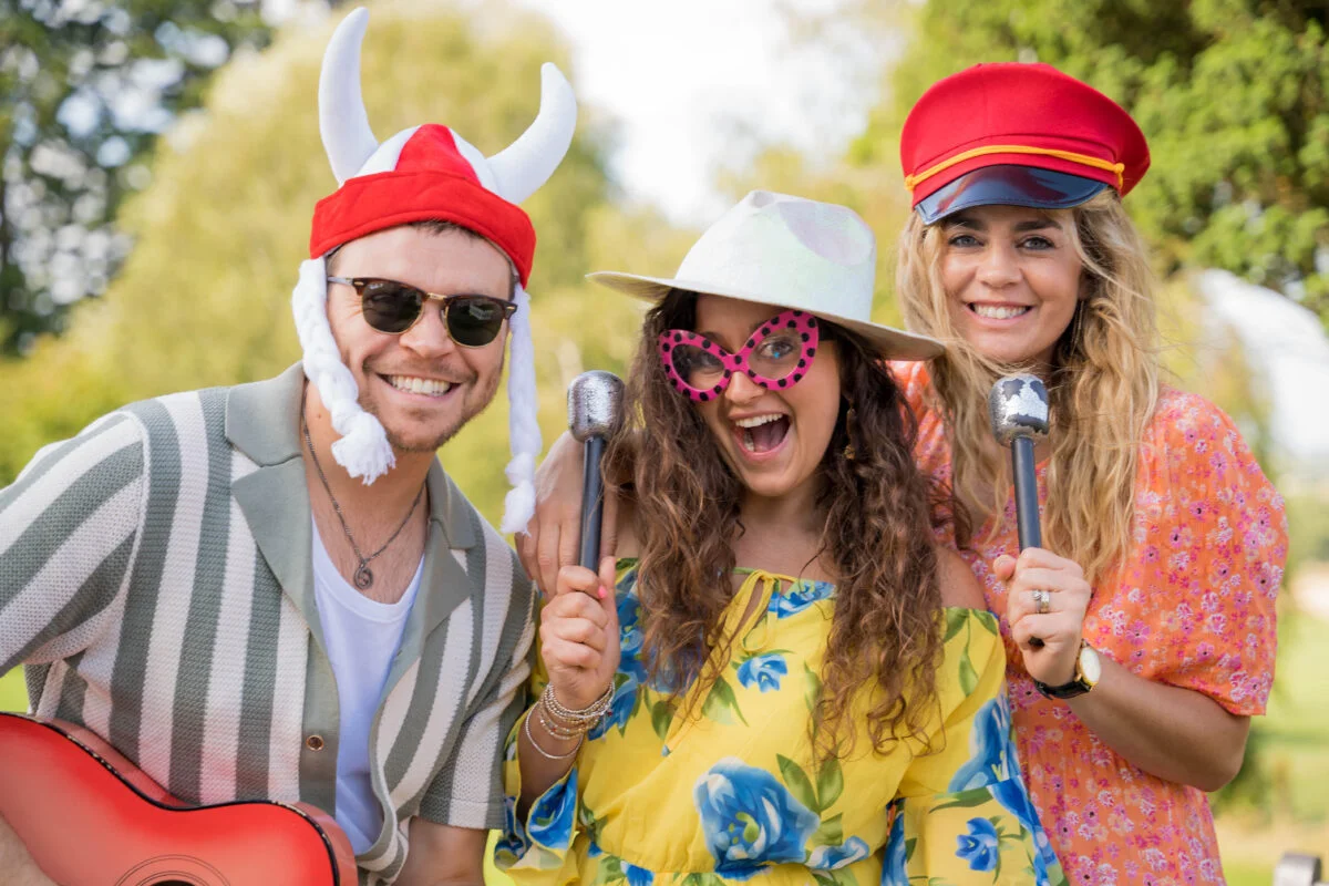 A group of people dressed up in hats and wigs with guitars and microphones.