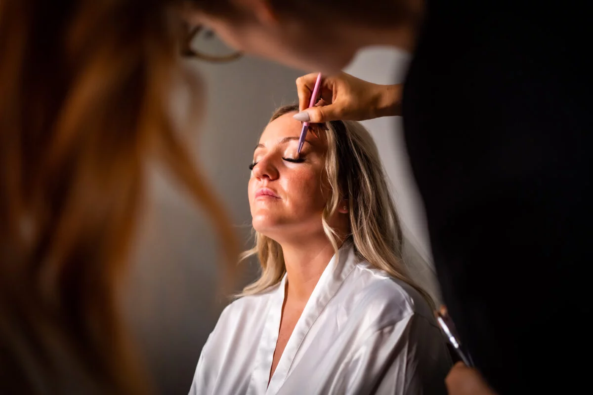 A bride getting her makeup done by a makeup artist.