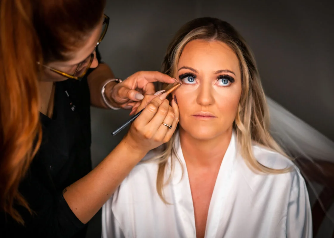 A bride getting her makeup done by a makeup artist.