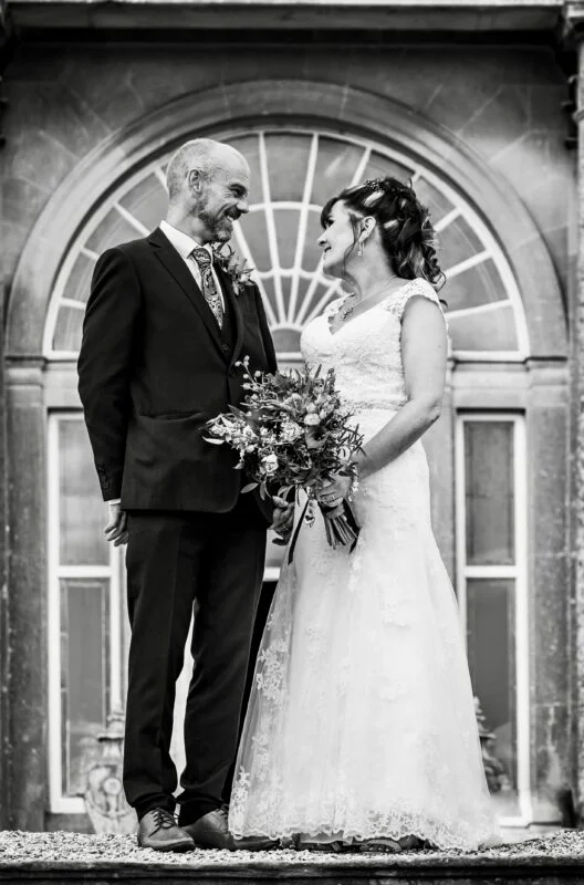 A bride and groom standing in front of an ornate building.