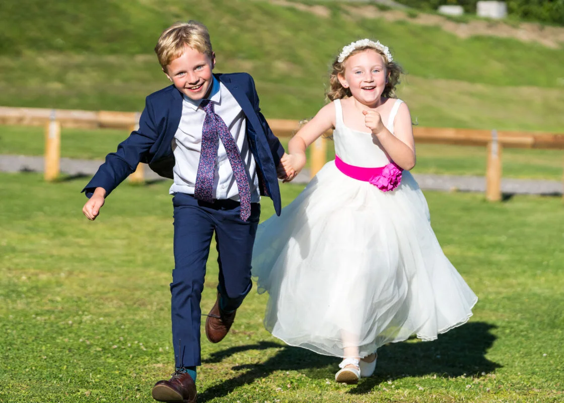 A boy and a girl running in a field.