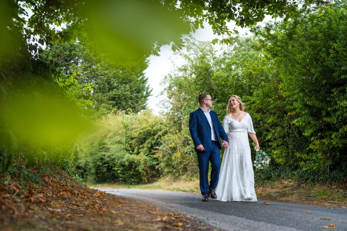A bride and groom walking down a country road.