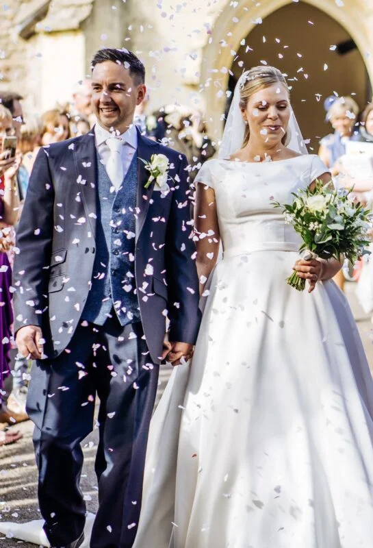 A bride and groom walking down the aisle with confetti thrown at them.
