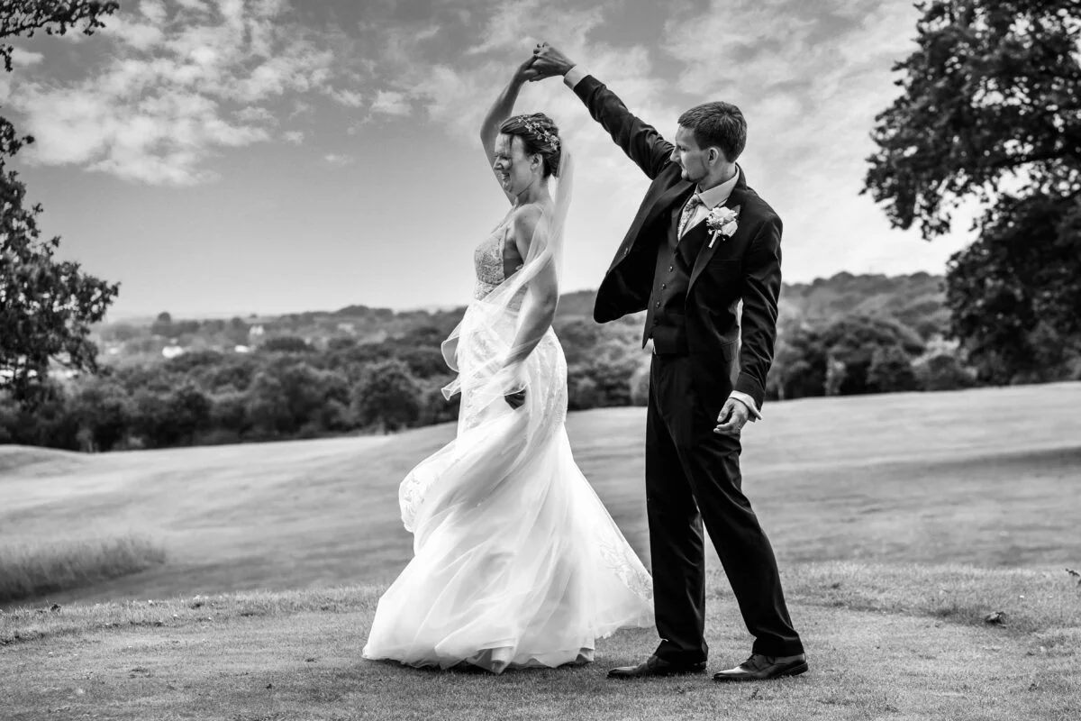 Black and white photo of a bride and groom dancing on a golf course.