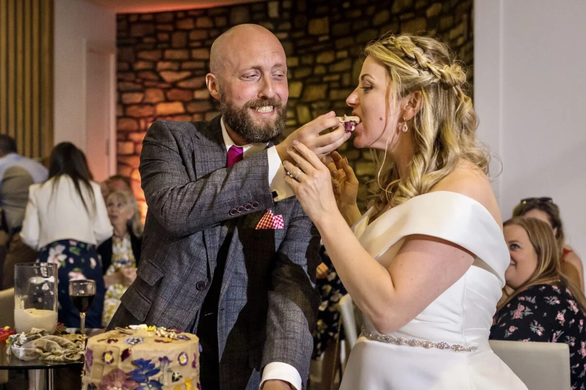 A bride and groom feeding each other their wedding cake.