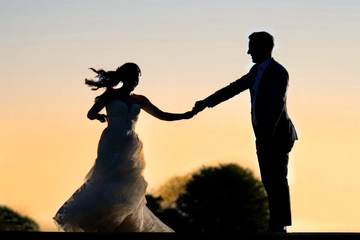A silhouette of a bride and groom dancing at sunset.