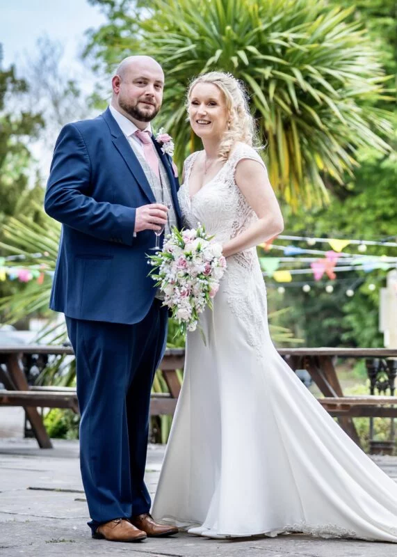 A bride and groom posing for a photo in a garden.