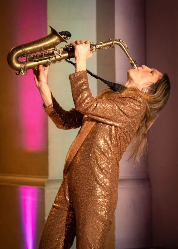 A woman in a gold suit playing a saxophone.