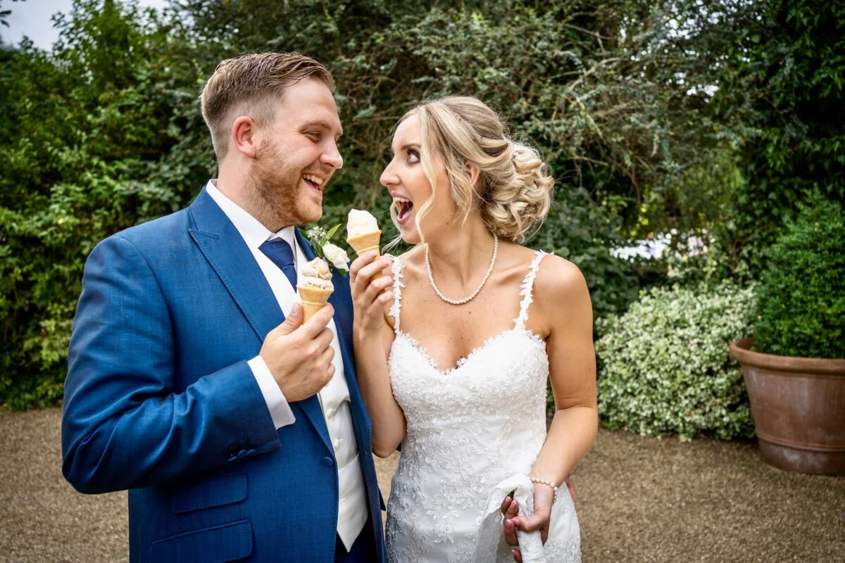 A bride and groom eating ice cream in a garden.