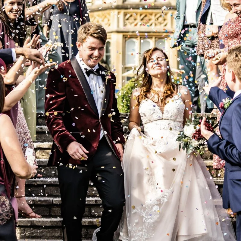 A bride and groom are surrounded by confetti at their wedding.