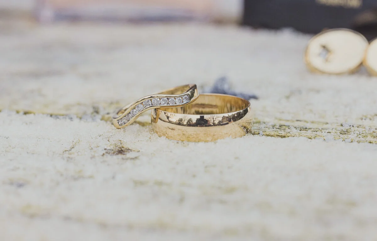 A pair of gold wedding rings laying on top of snow.