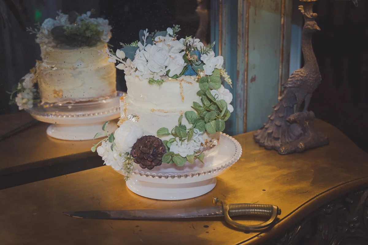 A wedding cake on a table in front of a mirror.