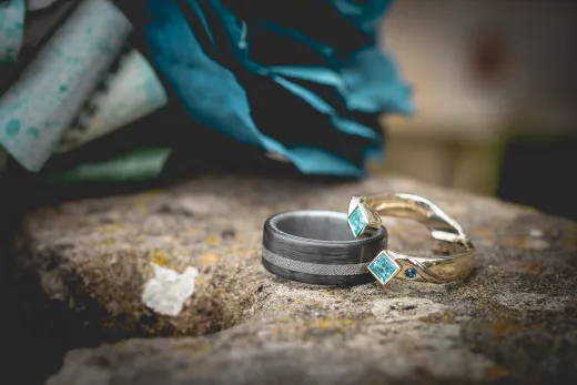 Two wedding rings sitting on a rock.