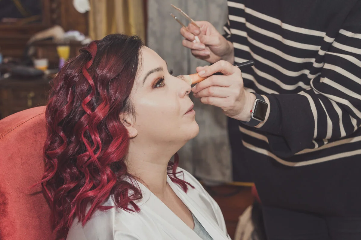 A woman getting her makeup done by a makeup artist.