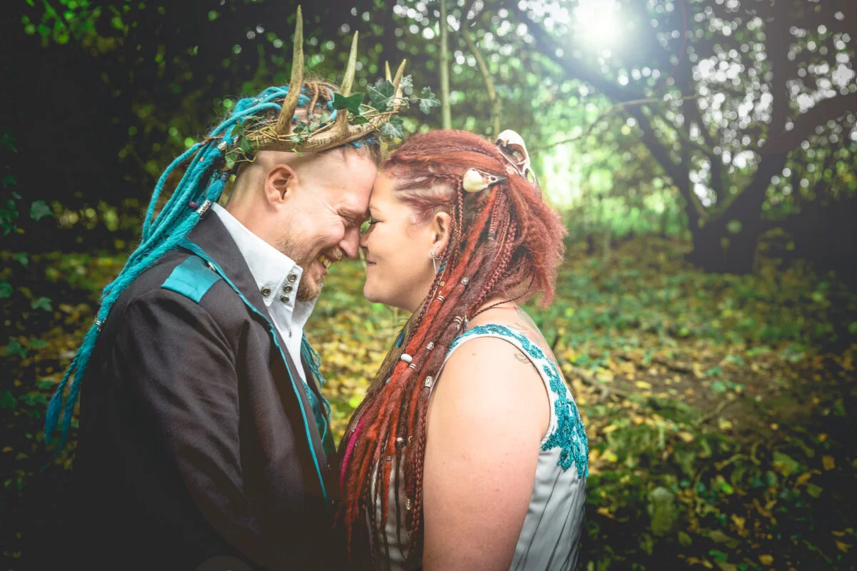A couple with dreadlocks and a crown in the woods.