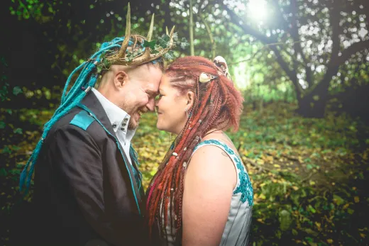 A couple with dreadlocks and a crown in the woods.