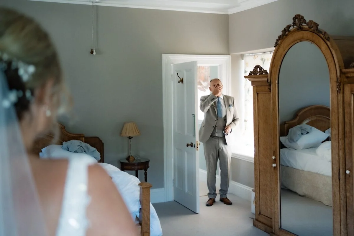 A bride and groom standing in front of a mirror.