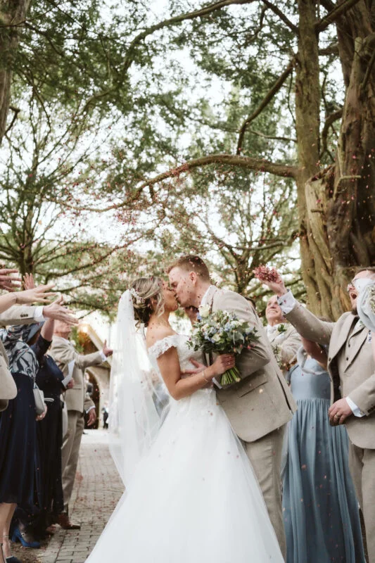 A bride and groom kissing in front of confetti.