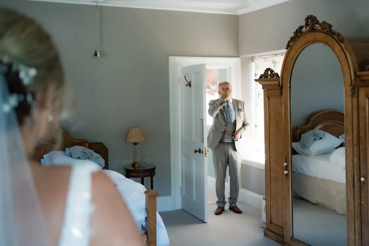 A bride and groom standing in front of a mirror.