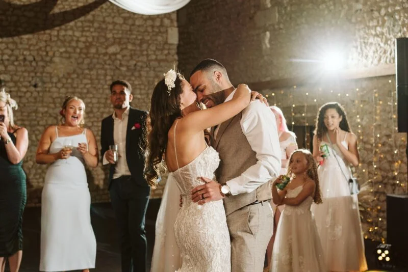 A bride and groom sharing their first dance in a barn.