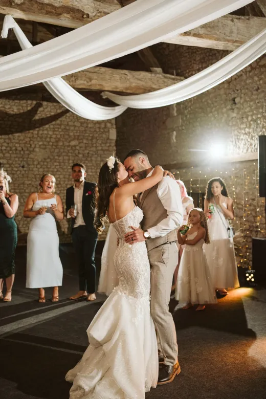 A bride and groom sharing their first dance in a barn.