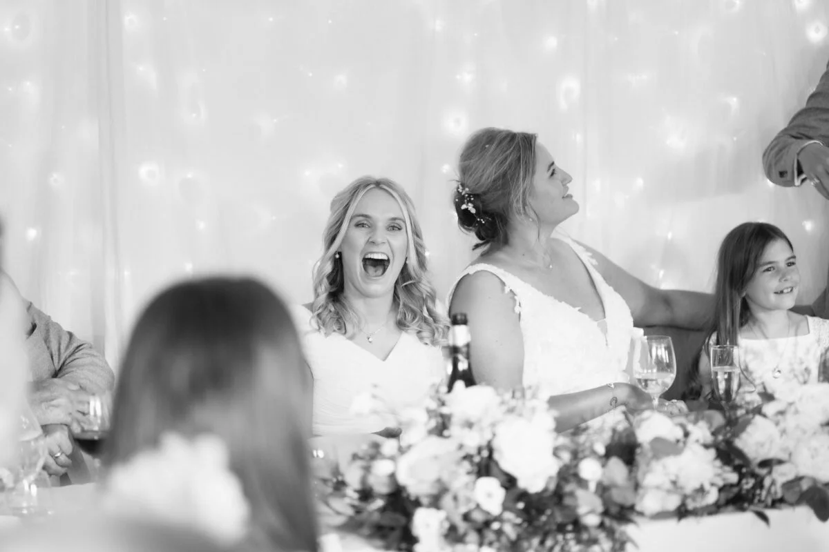 Black and white photo of a woman laughing at a wedding reception.
