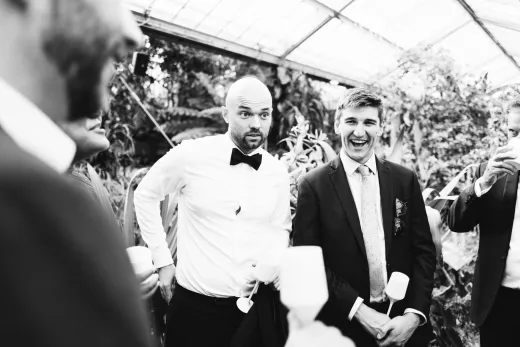 A black and white photo of a group of groomsmen in a greenhouse.