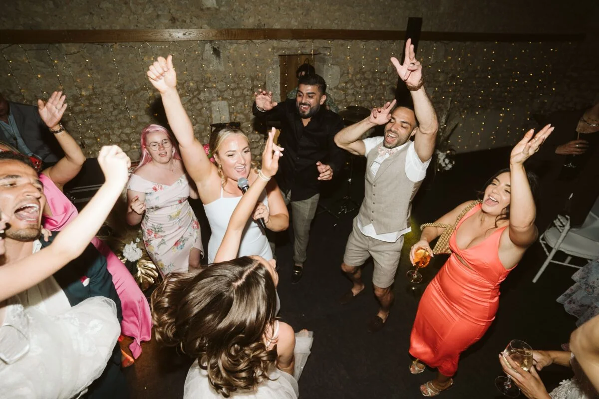 A group of people dancing at a wedding reception.