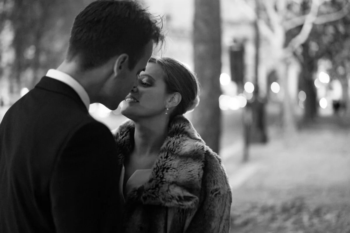 A black and white photo of a couple kissing in a park.