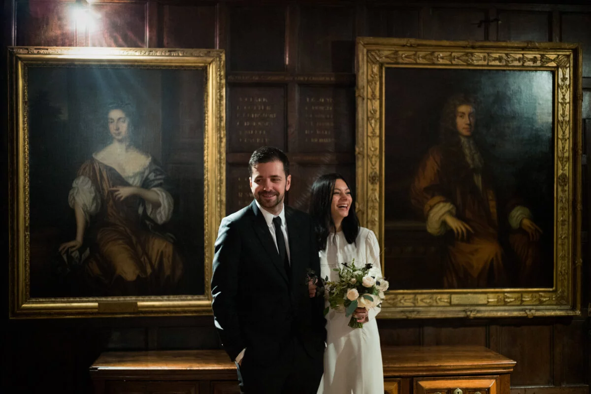 A bride and groom standing in front of paintings.