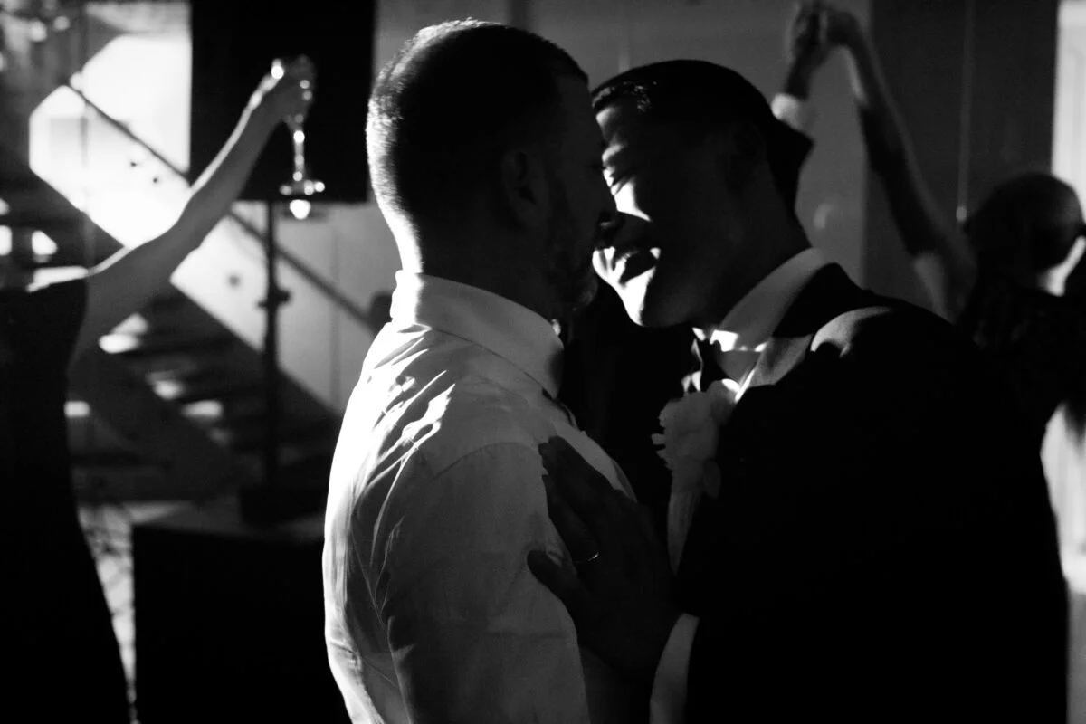 Black and white photo of a couple sharing a kiss on the dance floor.
