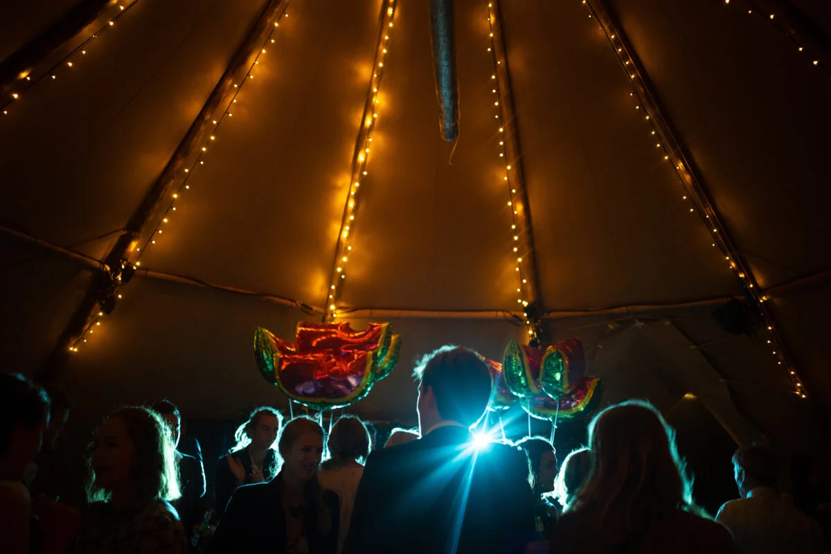 A group of people standing in a tipi at night.