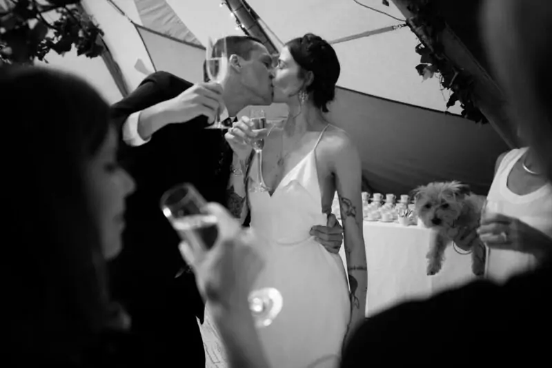A bride and groom kissing in front of a tent.