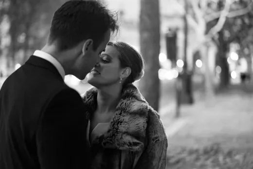 A black and white photo of a couple kissing in a park by a documentary wedding photographer.