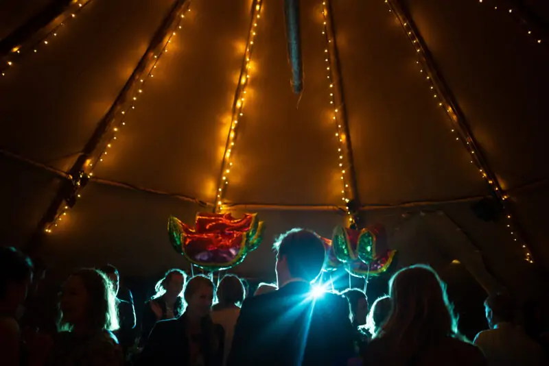 A group of people standing in a tipi at night.