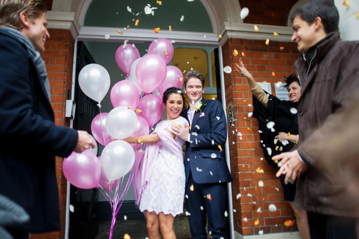 A man and a woman holding balloons in front of a door.