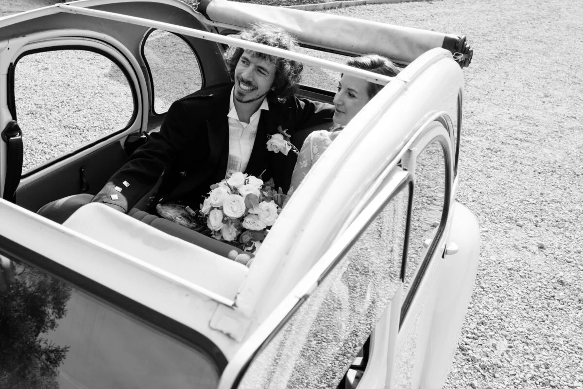 A black and white photo of a bride and groom in a car.