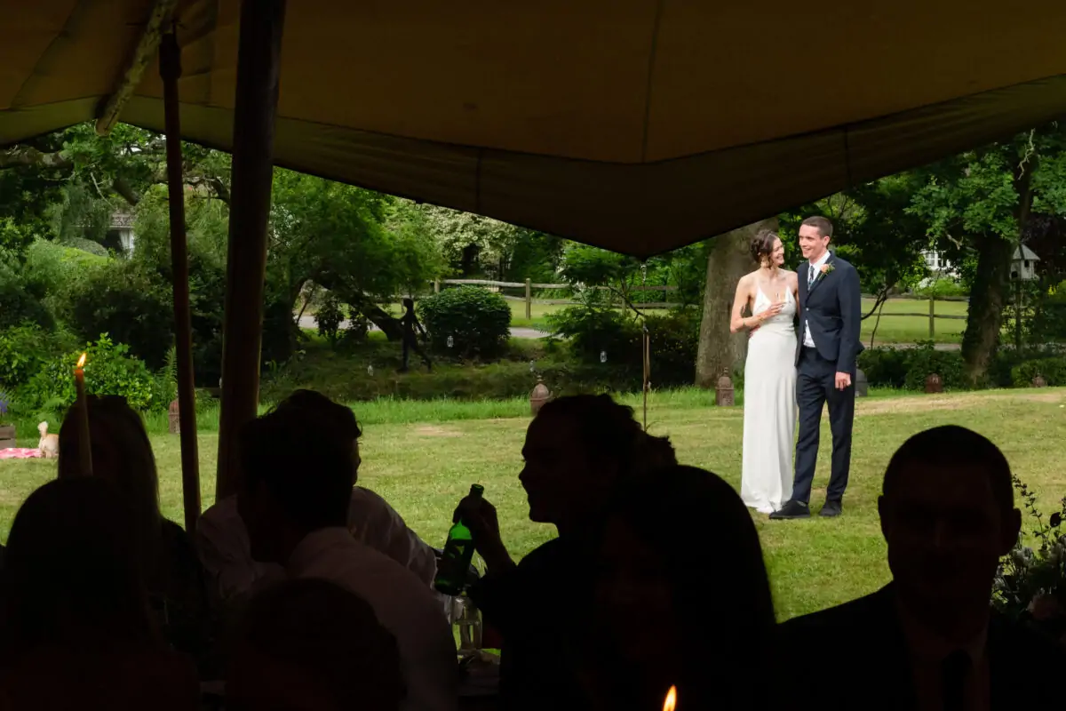 A bride and groom standing in front of a tent.