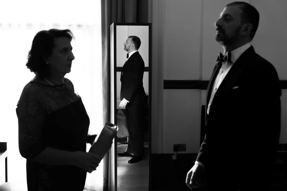 A man and woman standing in front of a mirror.