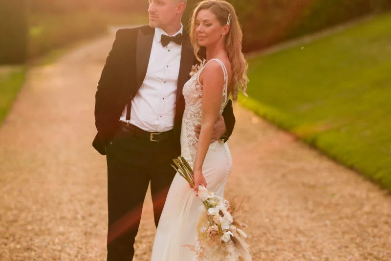 A bride and groom standing on a path in a garden.