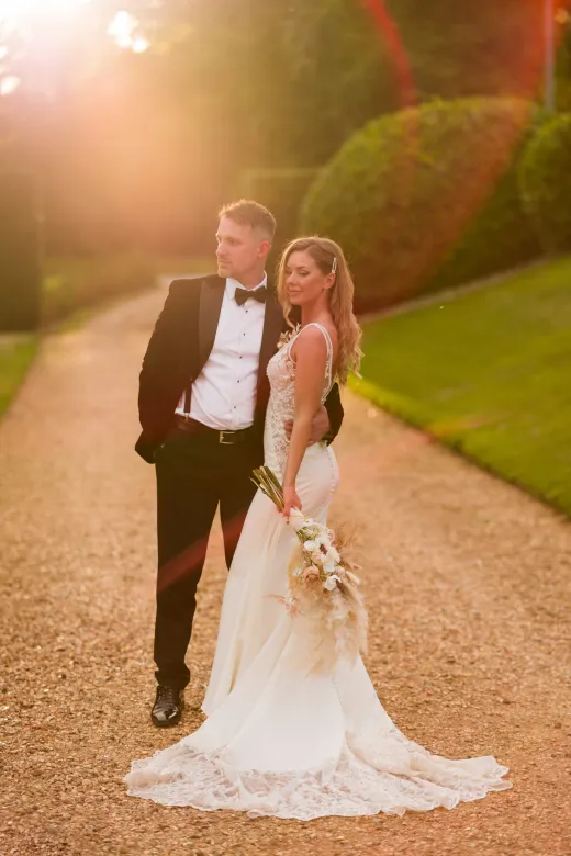 A bride and groom standing on a path in a garden.