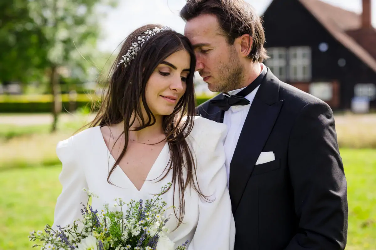 A bride and groom embracing in a field.
